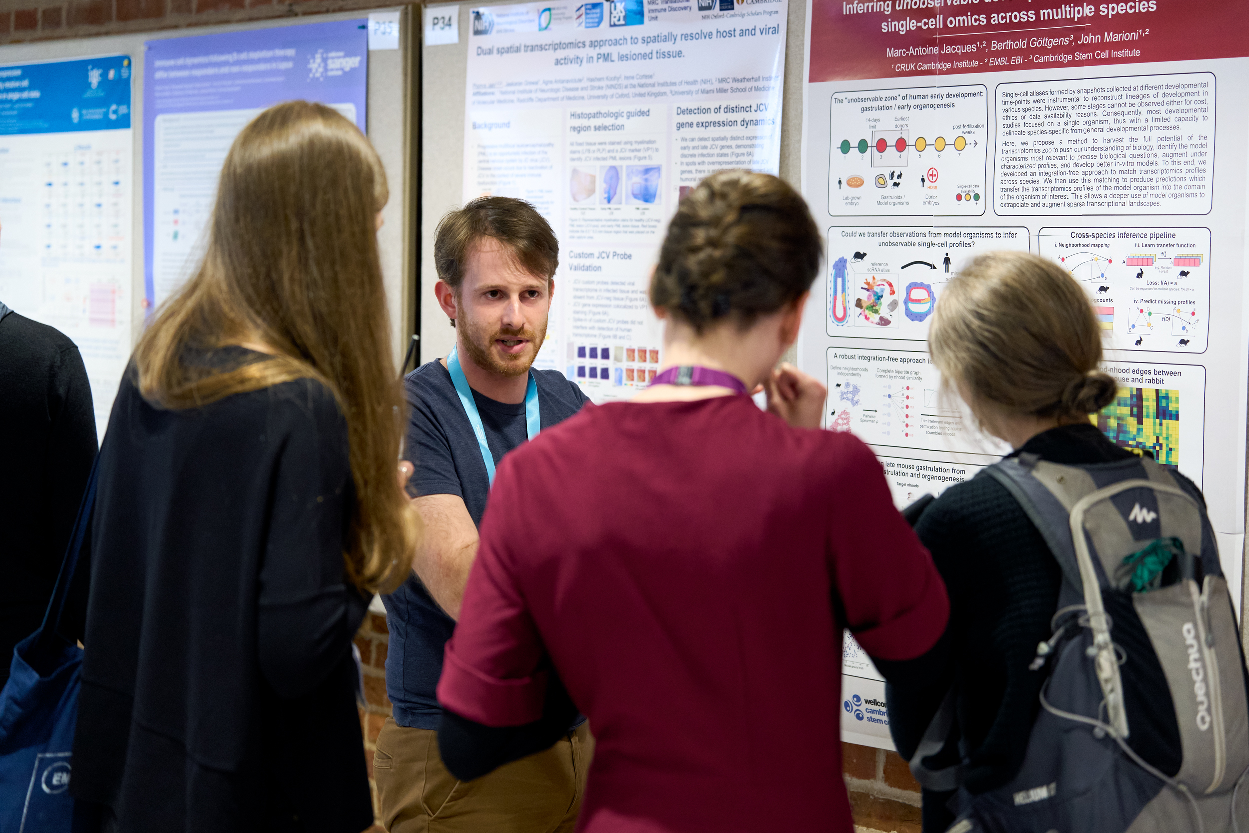 Conference delegate presenting single-cell omics and gene expression data on a scientific research poster, to three other attendees standing in an informal networking setting